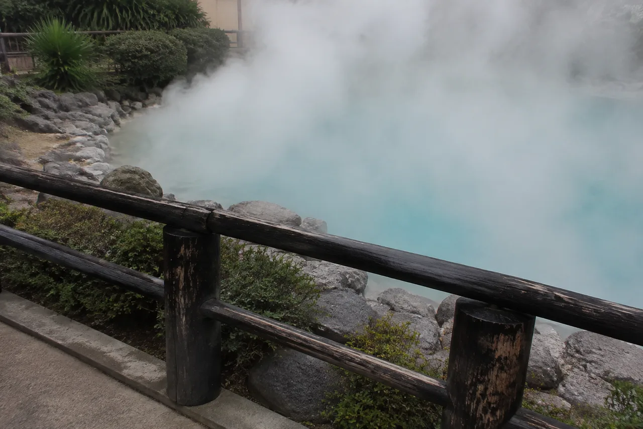 Wooden safety railing beside a steaming geothermal pool