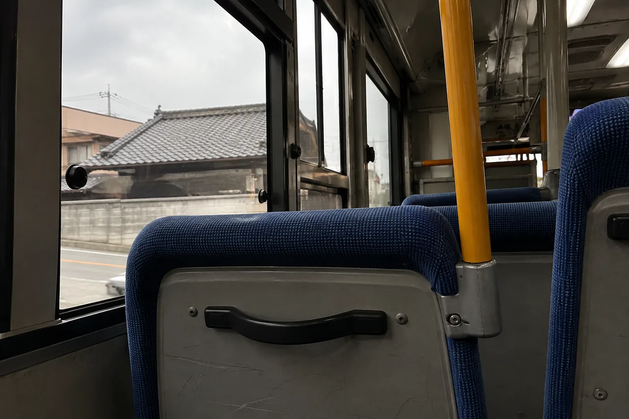 Blue seats and a handrail inside an empty local bus