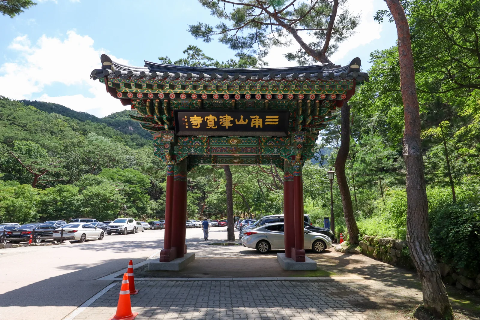 The entrance gate of Jingwansa with its signboard reading 三角山津寬寺, and forest behind