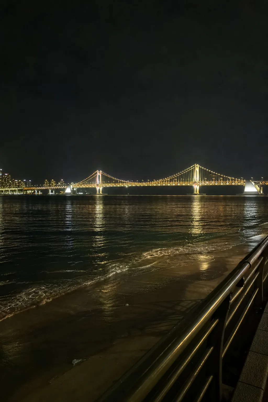 A lit suspension bridge across a bay at night
