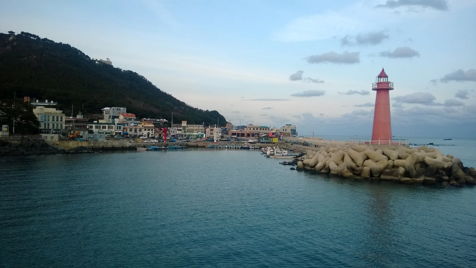 青沙浦防波堤末端的紅色燈塔,和山腳下的港口村落