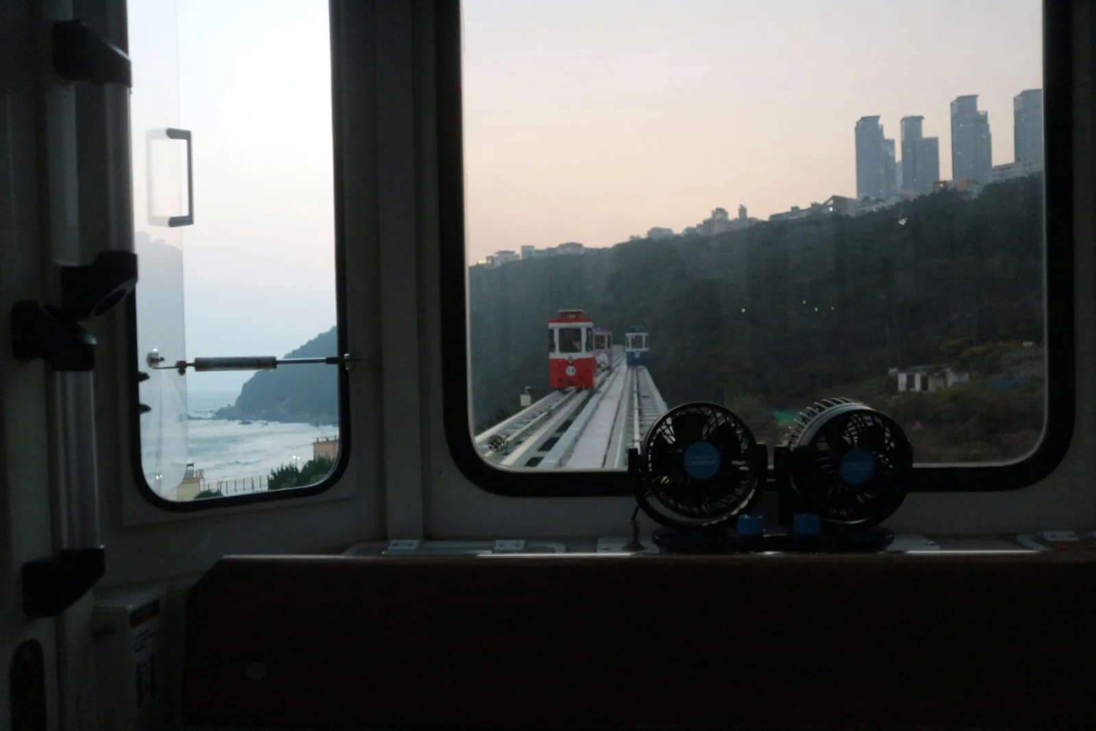 從天空膠囊列車內看出前窗,儀表板上有兩台小電風扇,軌道前方是一台紅色膠囊