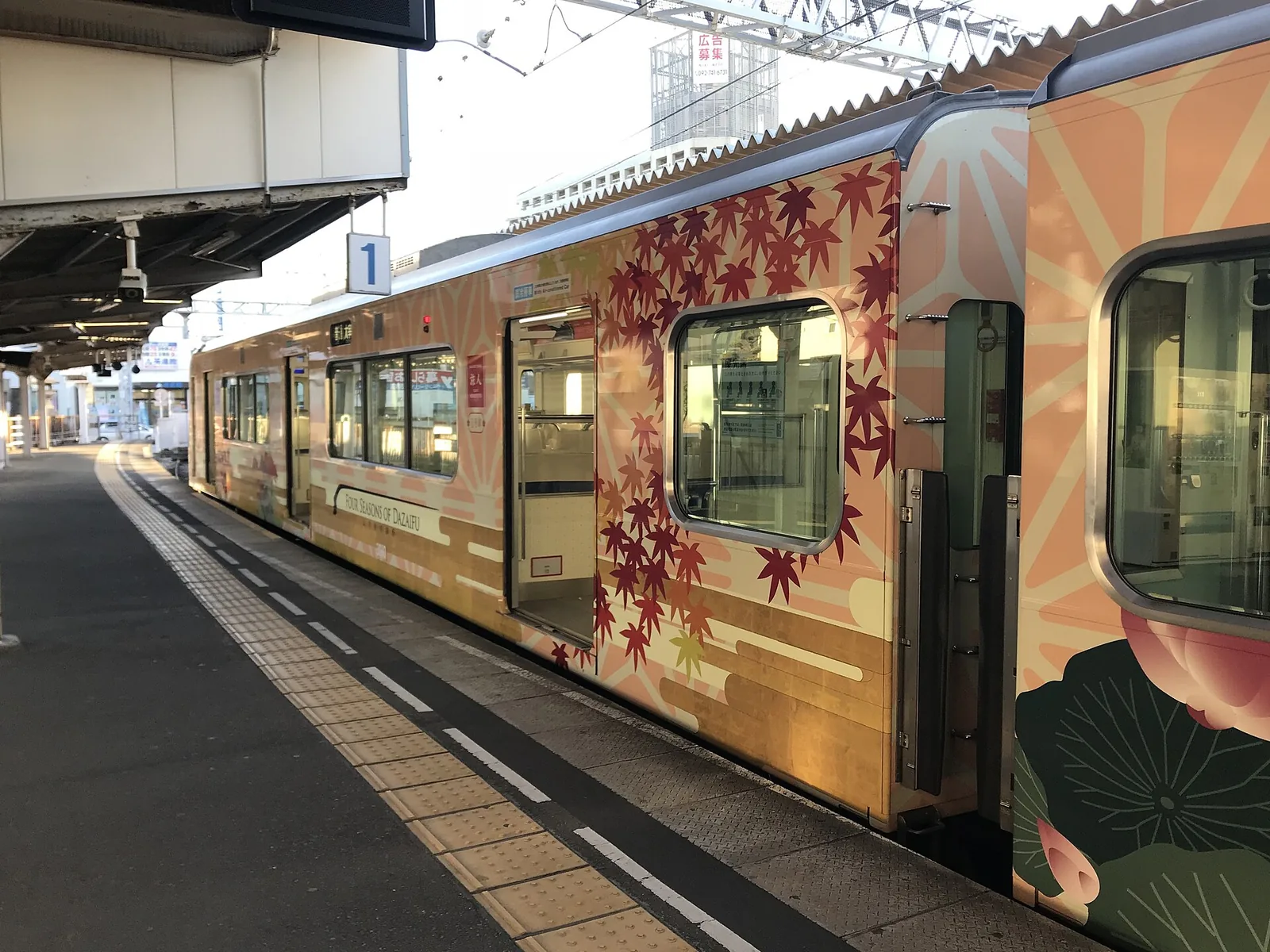 The Tabito sightseeing train, painted with autumn leaves and lotus flowers, standing at a platform at Nishitetsu Futsukaichi