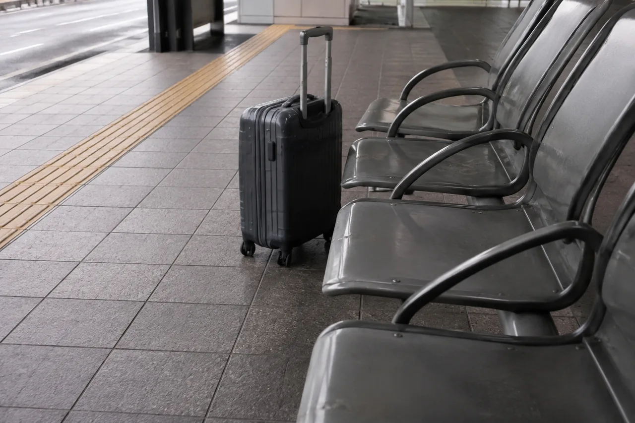 A suitcase beside seats in an airport bus waiting area