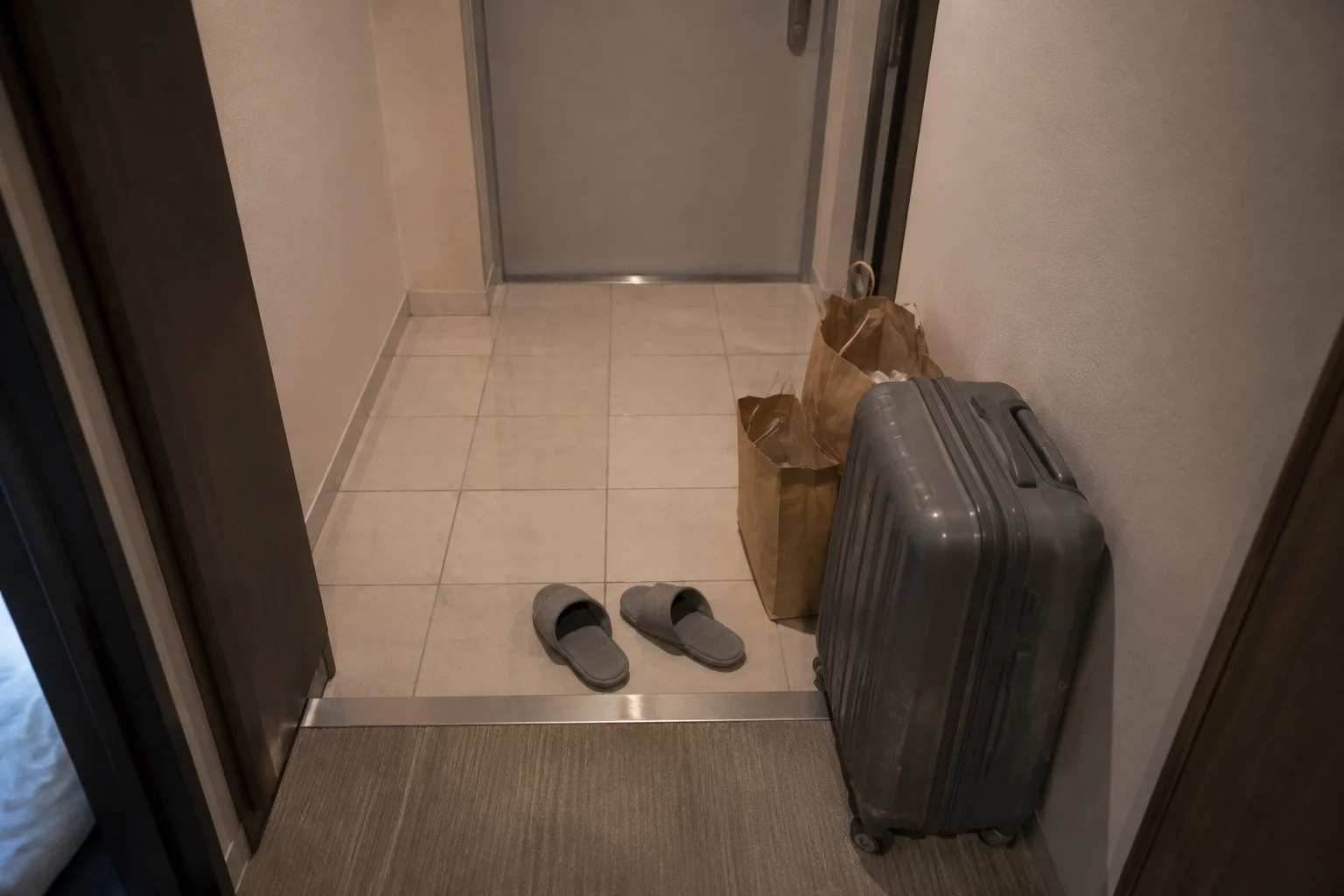A suitcase, slippers and paper bags in a compact lodging entryway