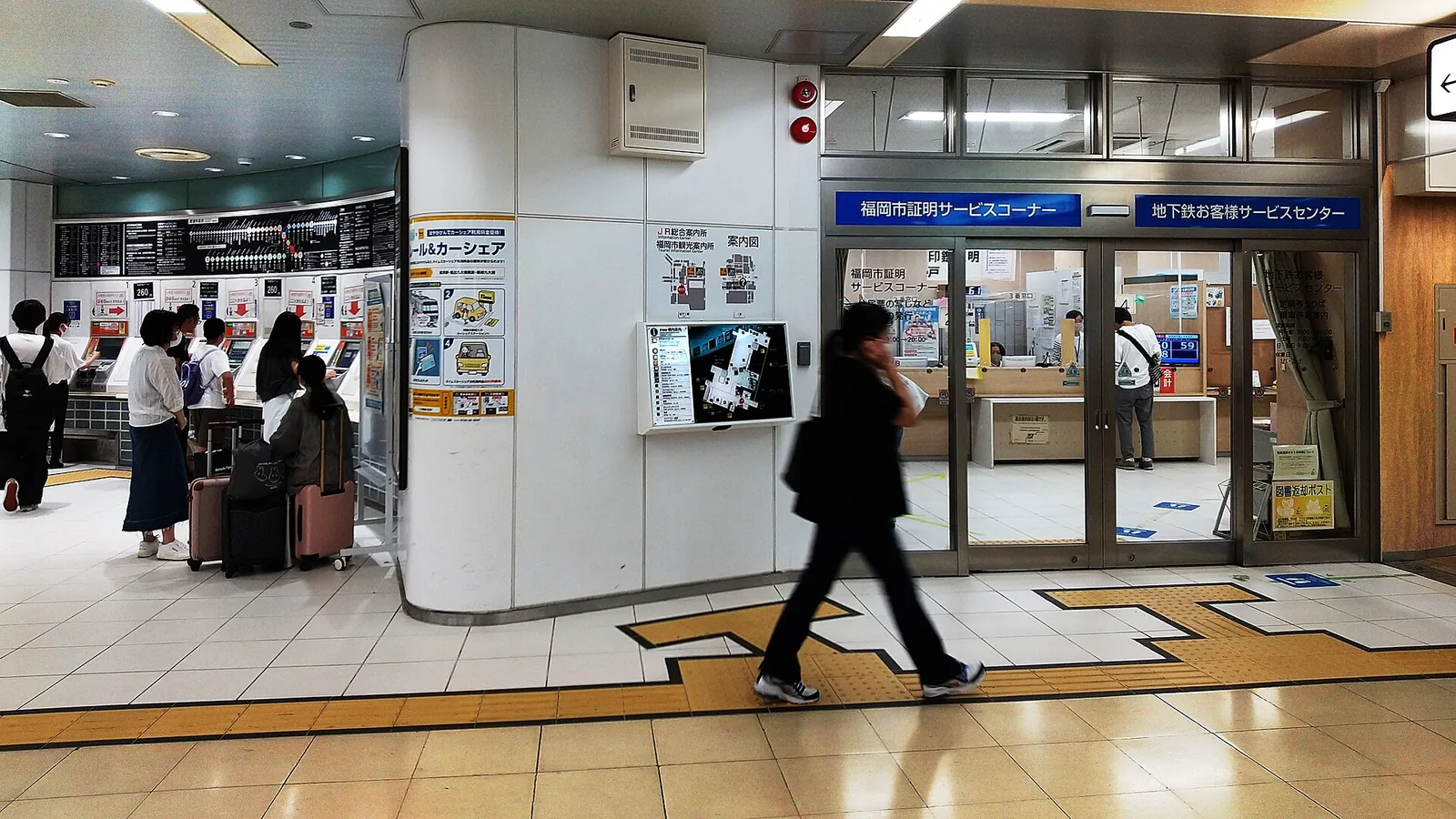 Travelers with suitcases at the ticket machines in Hakata subway station