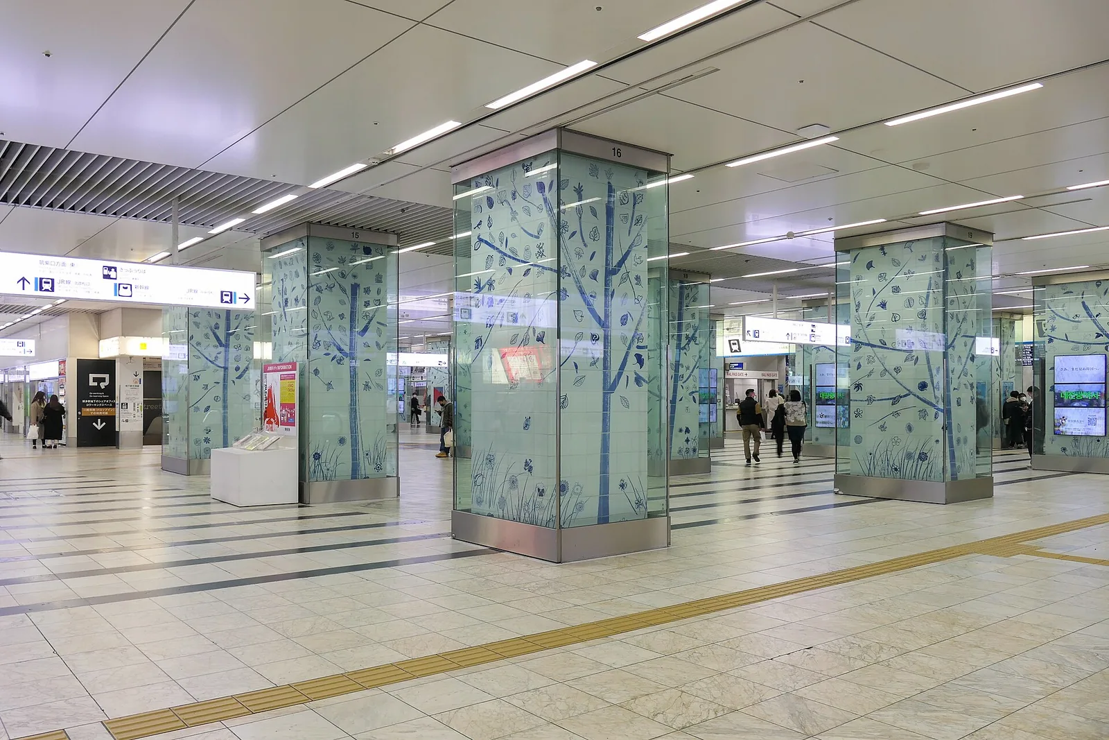 JR Hakata Station's first-floor concourse, lined with pillars decorated with a tree pattern