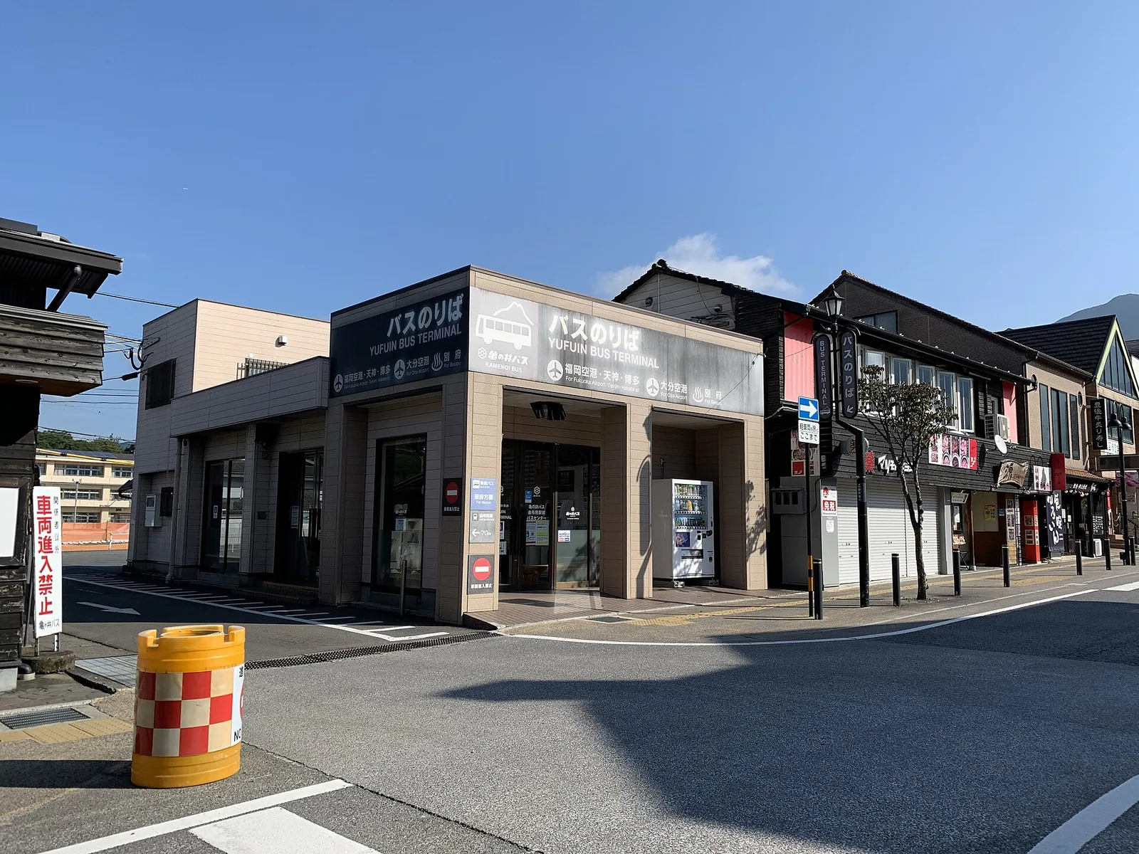 由布院站前一棟低矮建築，掛著日英文「Yufuin Bus Terminal」招牌，以及往福岡機場、天神、博多的指示牌