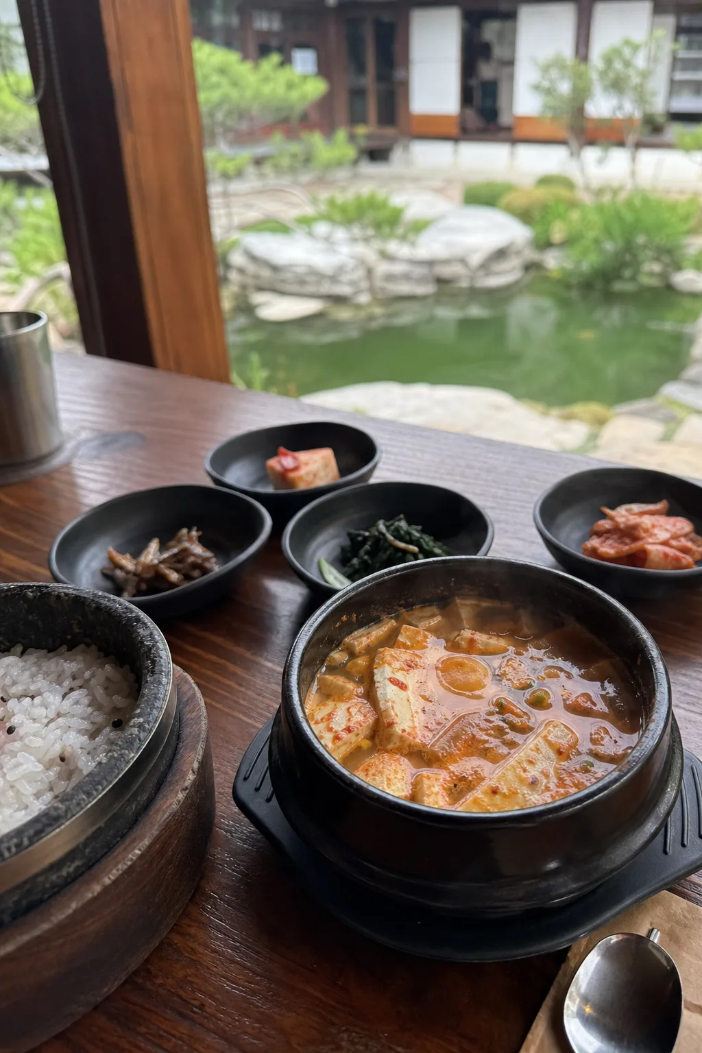 A bowl of spicy tofu stew with side dishes