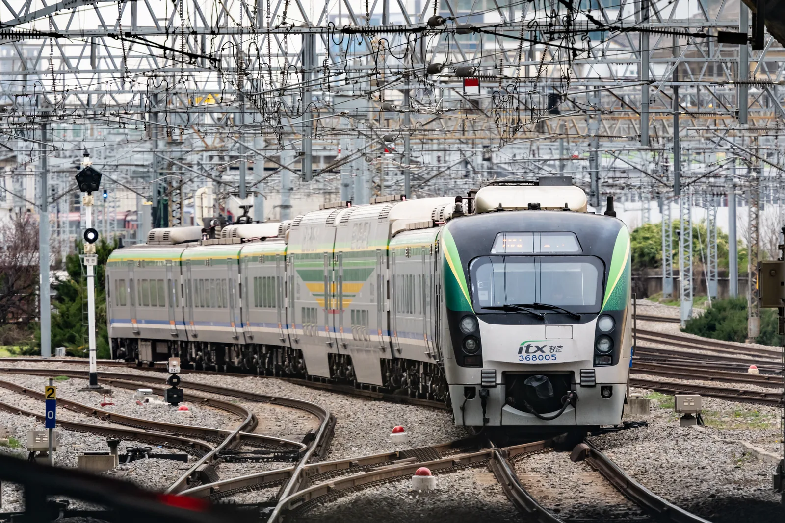 白色車身、綠黑色車頭的 ITX-青春列車駛過架空電線下的道岔