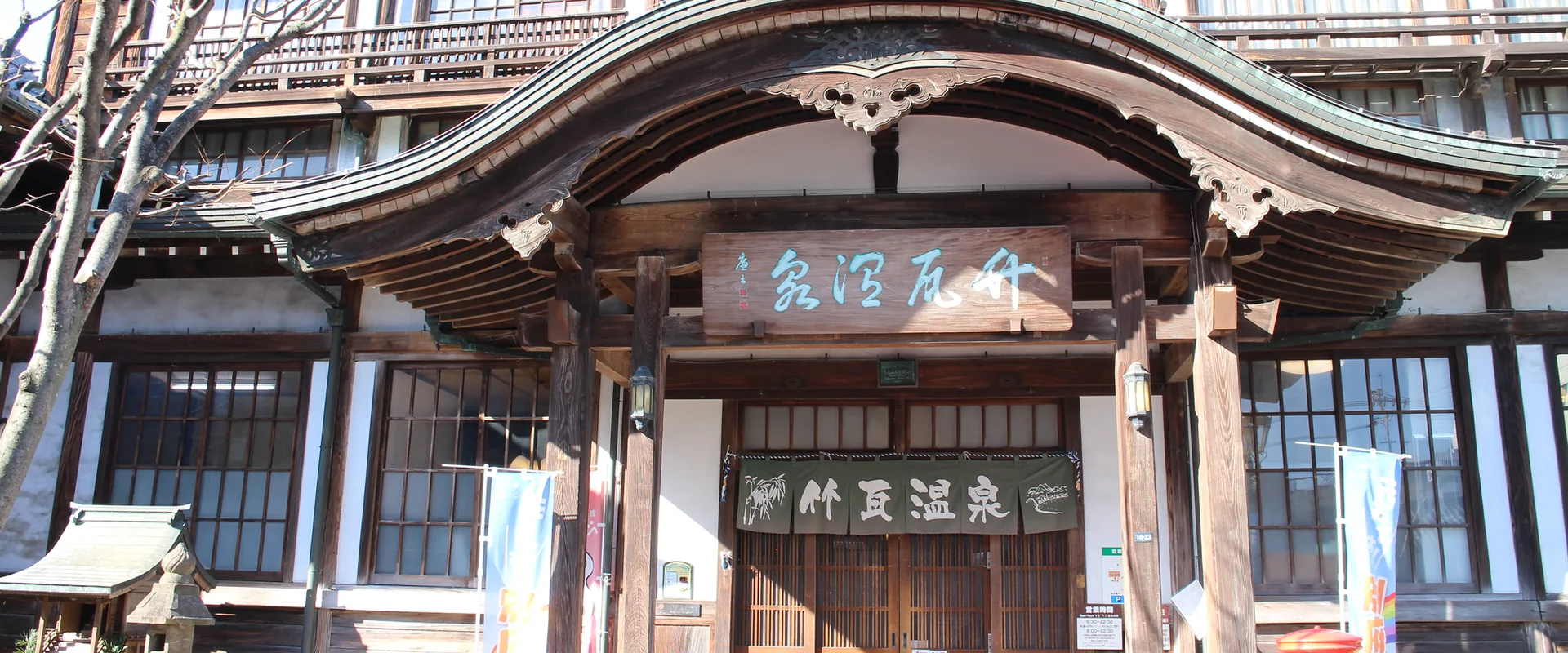 竹瓦溫泉正門，弧形的唐破風屋頂下掛著「竹瓦温泉」匾額，門口垂著暖簾