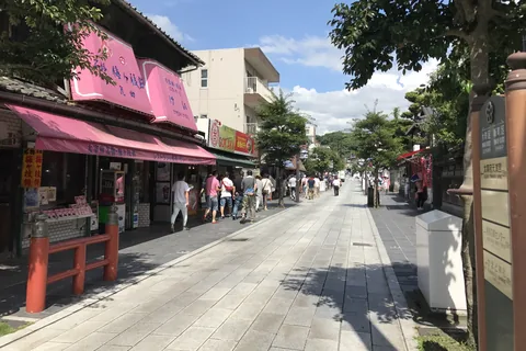 The shrine approach in Dazaifu, a paved street lined with souvenir and sweet shops under a blue sky