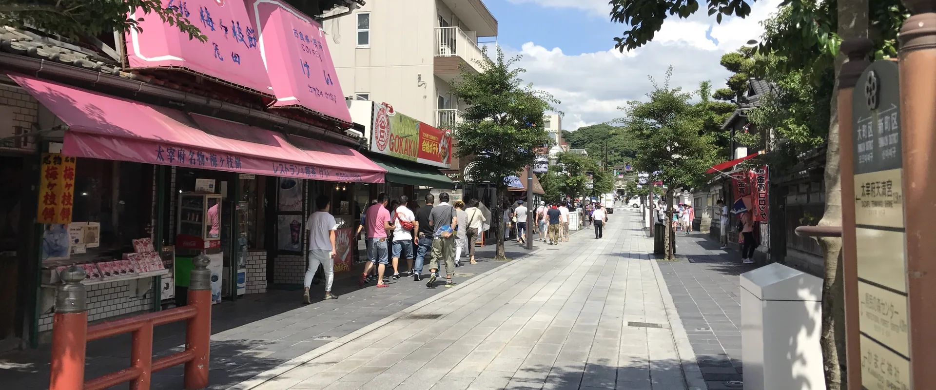 The shrine approach in Dazaifu, a paved street lined with souvenir and sweet shops under a blue sky