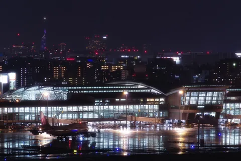 Fukuoka Airport's International Terminal at night, a jet at the gate and the city's lights behind it