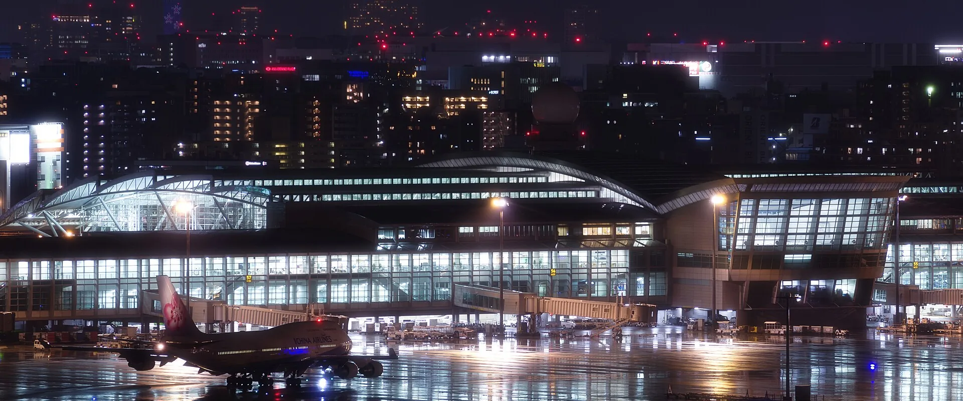 Fukuoka Airport's International Terminal at night, a jet at the gate and the city's lights behind it