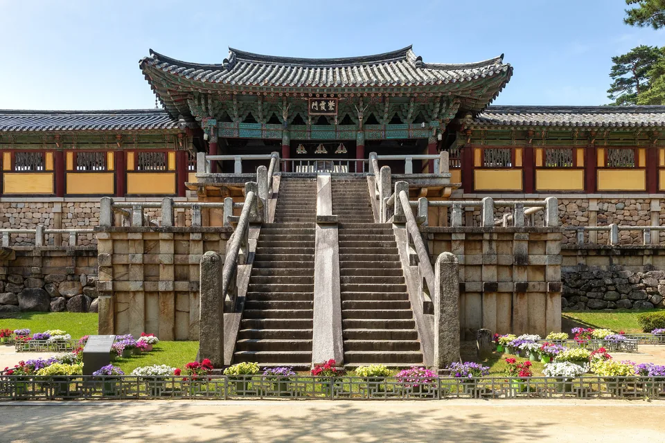 The stone Cheongungyo and Baegungyo stairways rising to Jahamun Gate at the front of Bulguksa, behind a bed of flowers