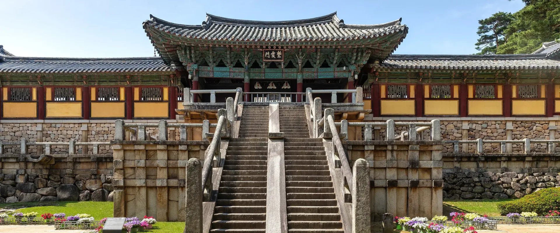 The stone Cheongungyo and Baegungyo stairways rising to Jahamun Gate at the front of Bulguksa, behind a bed of flowers