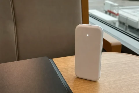 A small white pocket WiFi router on a table beside an airport window