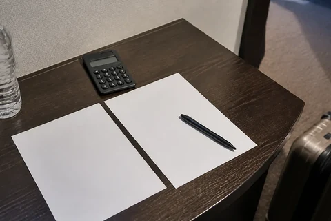 A calculator and blank planning sheets beside luggage