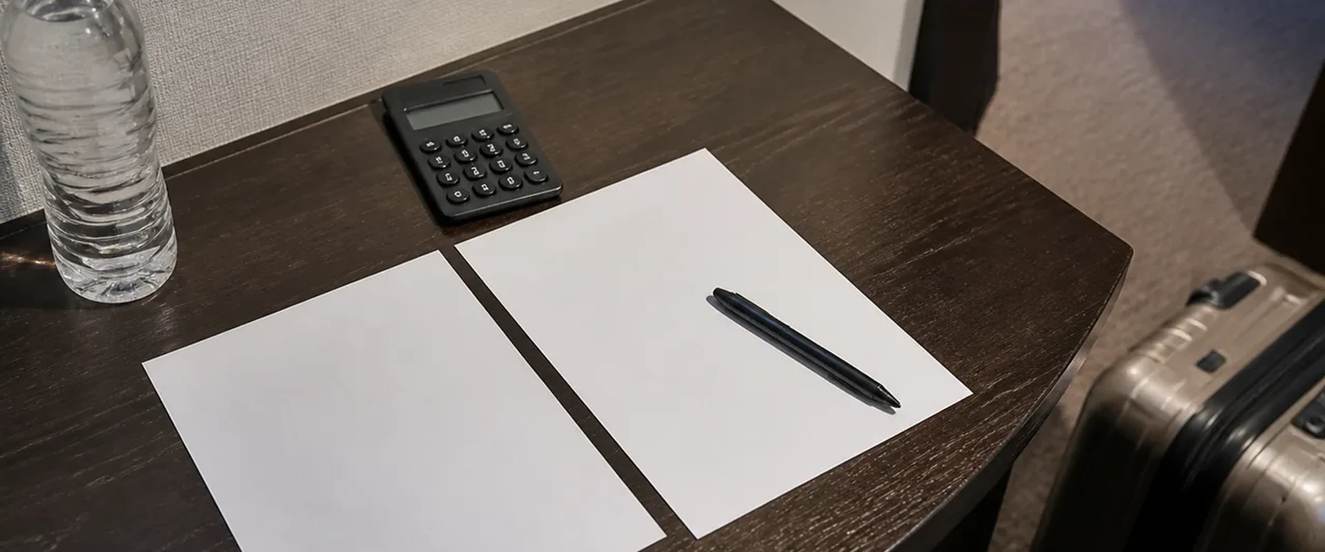 A calculator and blank planning sheets beside luggage