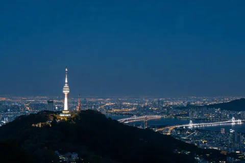 A lit tower above a city skyline at night