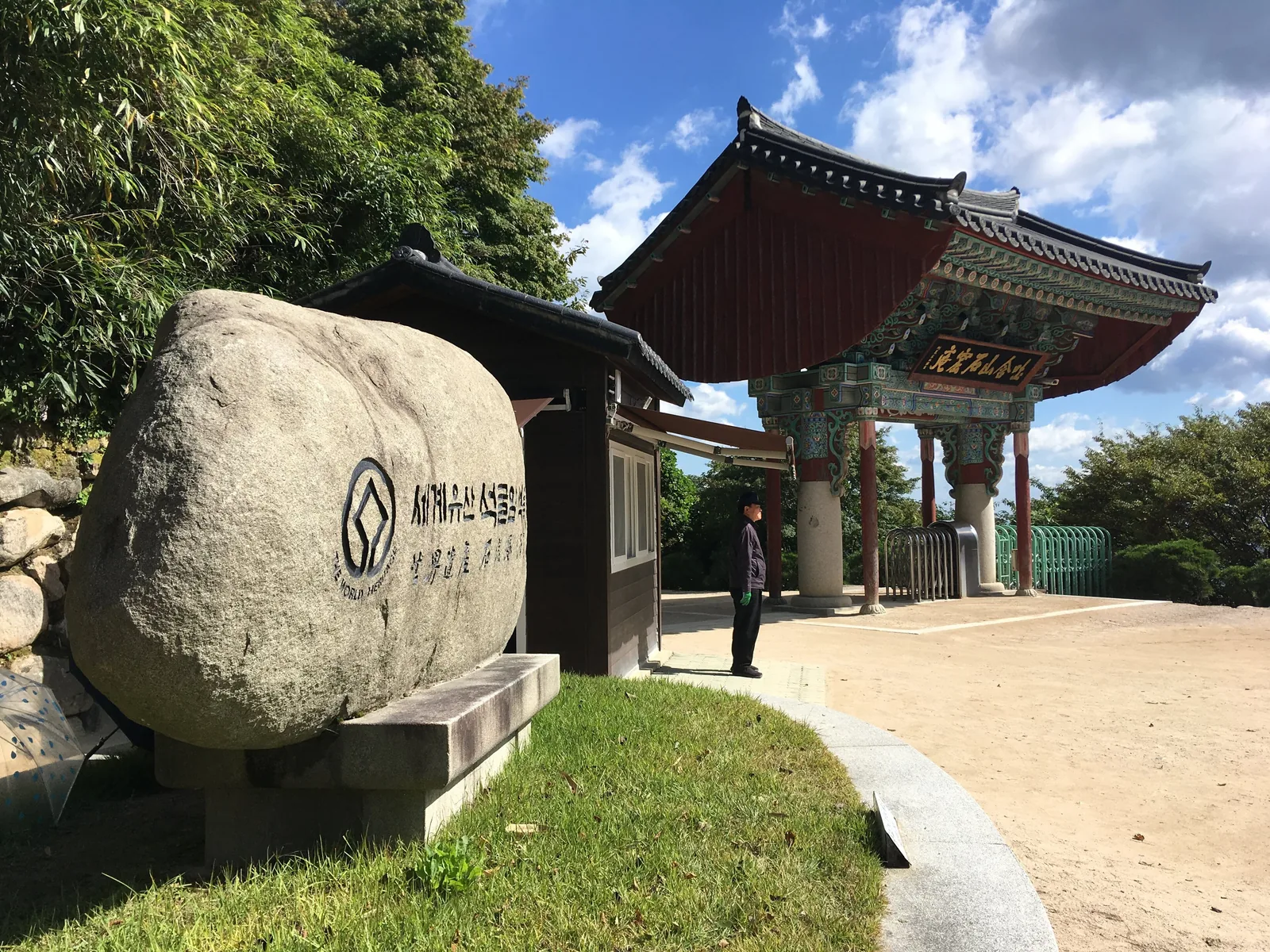 Seokguram's Iljumun gate with its painted roof, beside a large stone carved with the World Heritage emblem