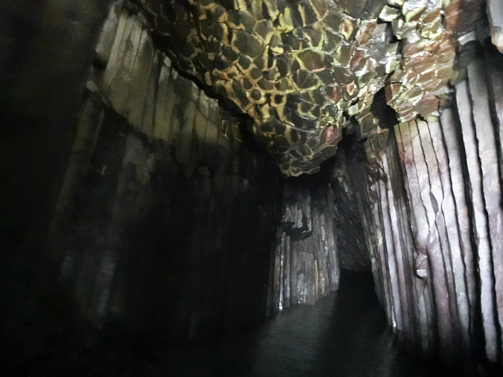 Inside the Keya-no-Oto sea cave seen from the bow of the tour boat, a channel of water between walls of vertical basalt columns
