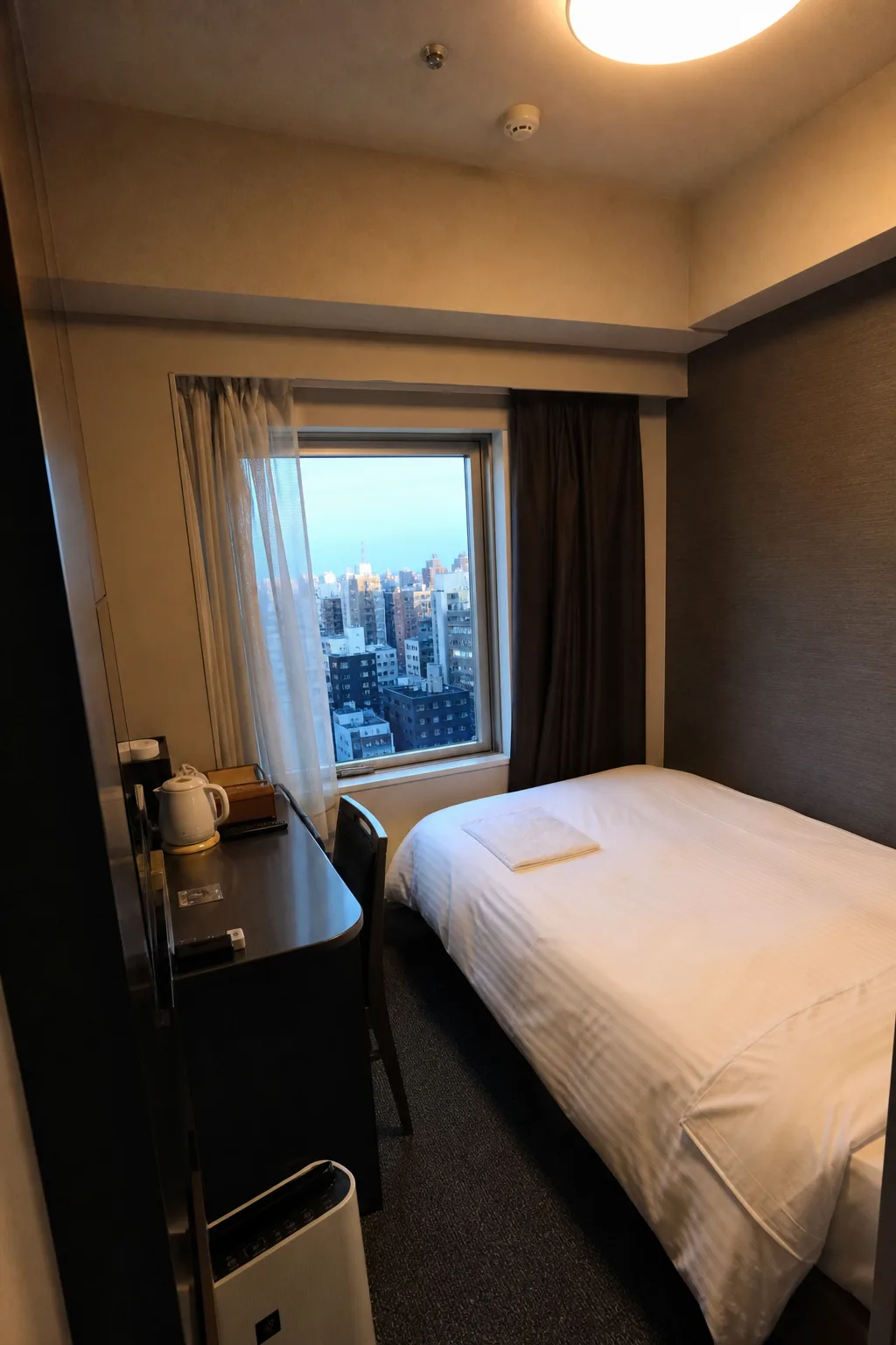 Compact business hotel room with a narrow bed and small desk