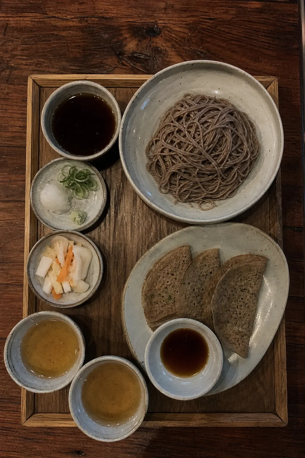 Buckwheat noodles, dipping sauce and side dishes on a wooden tray