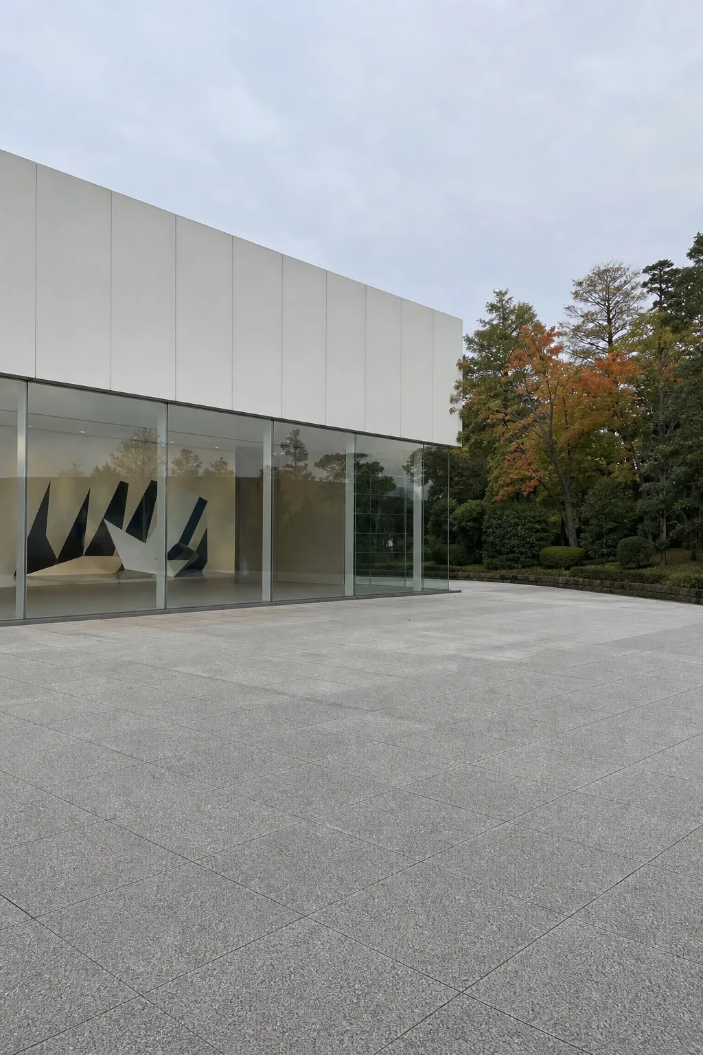 Modern glass-walled museum building beside a paved plaza
