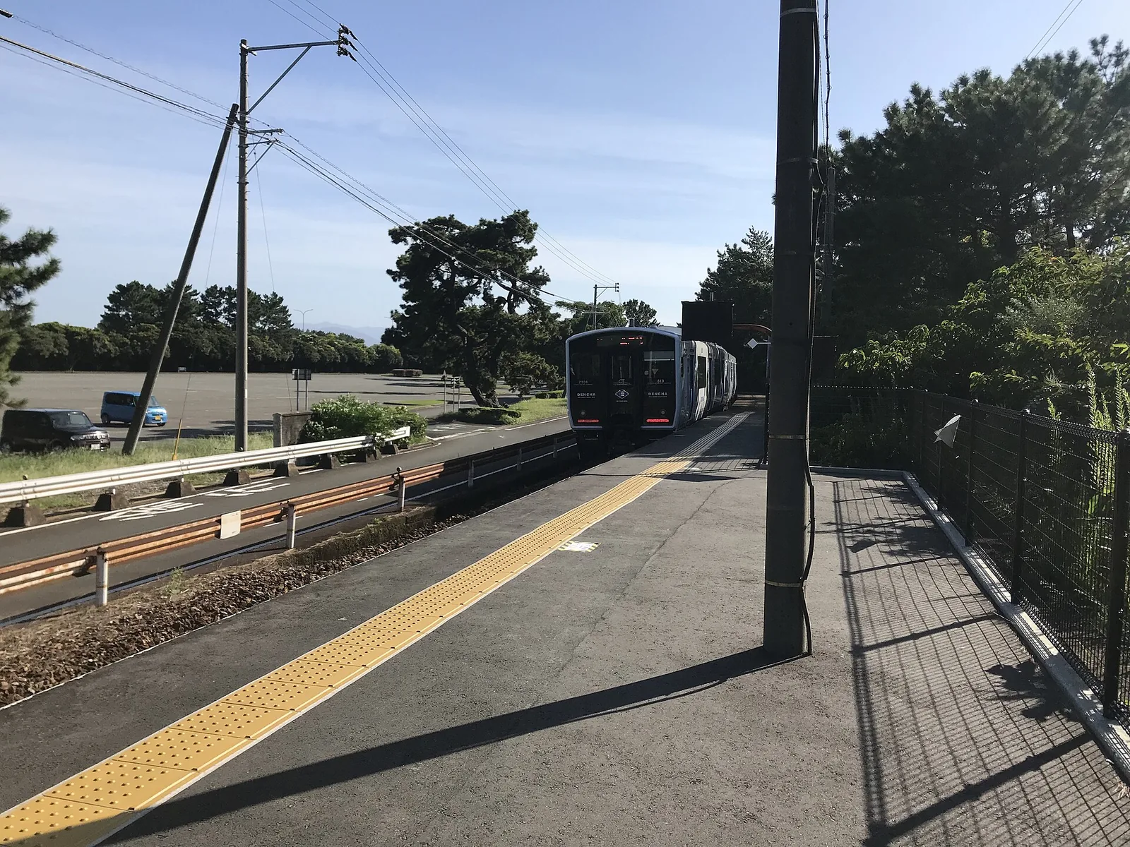 A Kashii Line train standing at the end of the pine-lined platform at Uminonakamichi Station